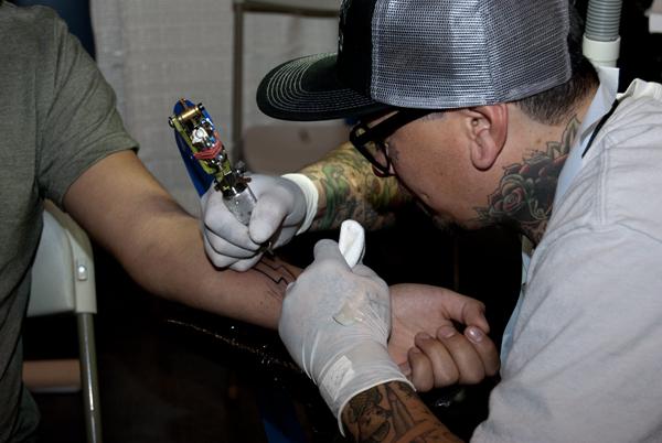 Tattoo artist, Brandon B. doing his first convention tattoo during Fresno Tattoo Convention on April 27, 2013. Brandon B.  works at Friendly City Tattoo in  Cotati, Calif. (Photo/Karen West)