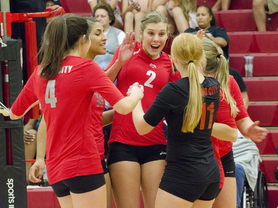 Jenna Goldsberry (4), Sydney Molander (2), and Carly Kosinski (11) celebrate on the court. 