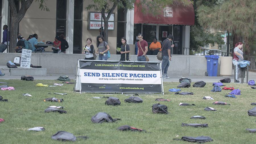 During a suicide awareness event, student gaze at dozens of backpacks laid out with messages about the thousands of lives lost each year to suicide.