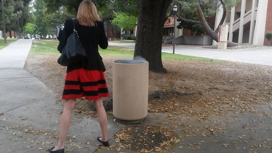 A woman looks into a trash can that had smoke rising from it on Thursday, April 7, 2016. 