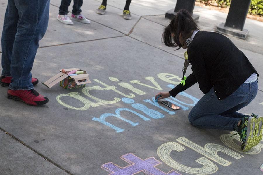 Elizabeth Pichardo, representative for the Fresno City College Active Minds Club draws on a sidewalk at the College Mall on Thursday, April 22, 2016. 