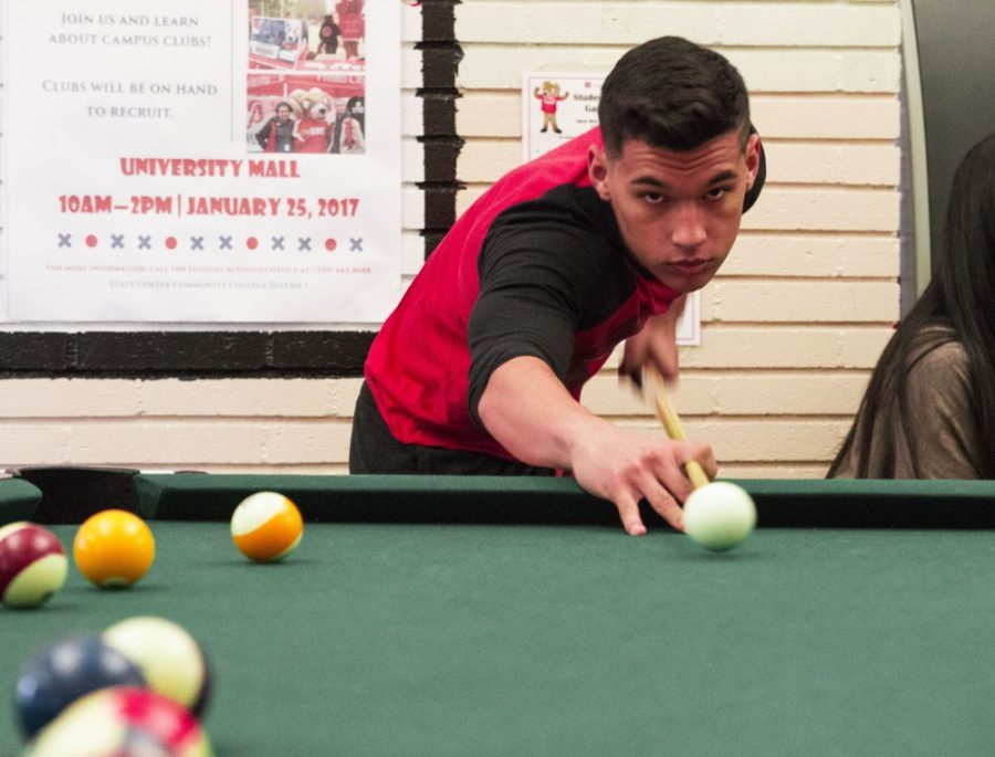 Joshua Alvarado making his shot into the corner pocket  in the game room at Fresno City College on Jan. 23, 2017.