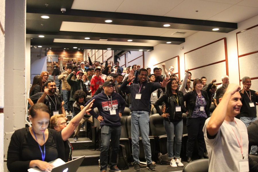 DevFest atendees follow keynote speaker Claire Slattery in a superhero pose exercise in BitWise Industries auditorium on Sunday, Oct. 22. 