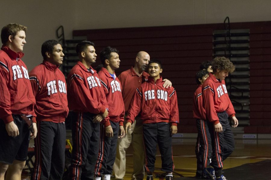 Fresno City College wrestling head coach Paul Keysaw (center) talks to his wrestler before a duel at home.