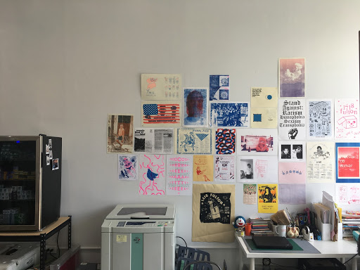 Riso printer and Zine prints hung on the wall in the shop.
