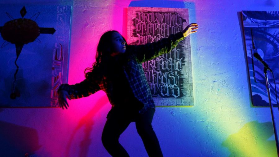 Dhani Del Toro dances in a dark lit room. 