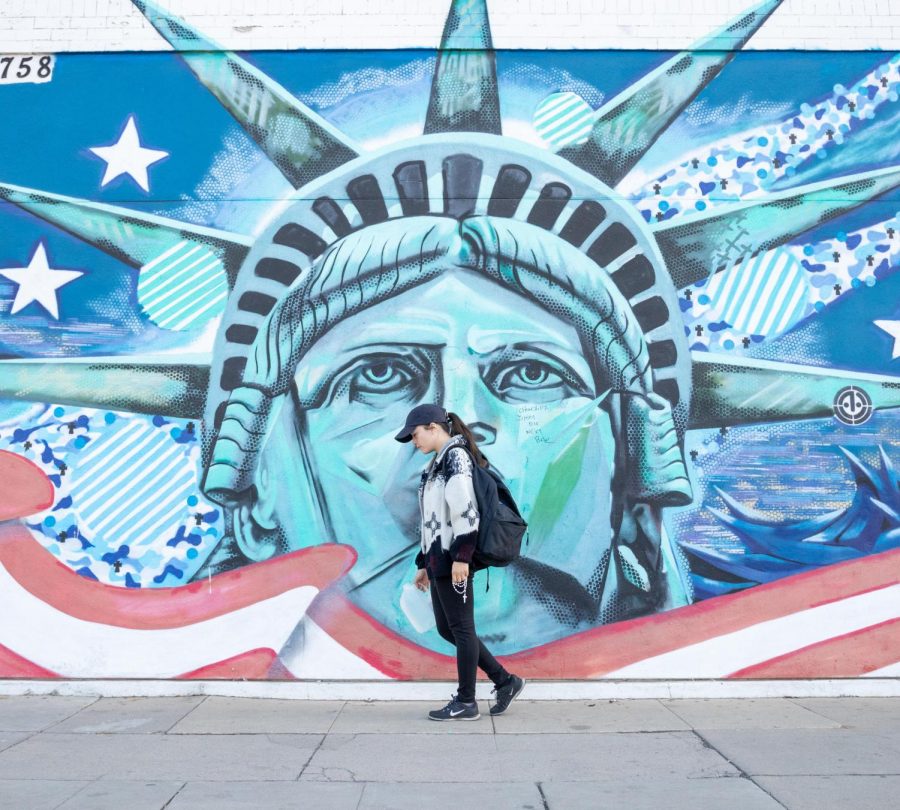 Dreamer Jackie Garcia holds items that represent her journey from Mexico to the U.S. in front of the Statue of Liberty mural at the Amvets in Downtown Fresno on Saturday, Nov.2, 2019.