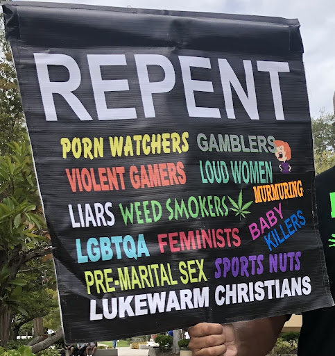 Man holding a sign while preaching at Fresno City College.