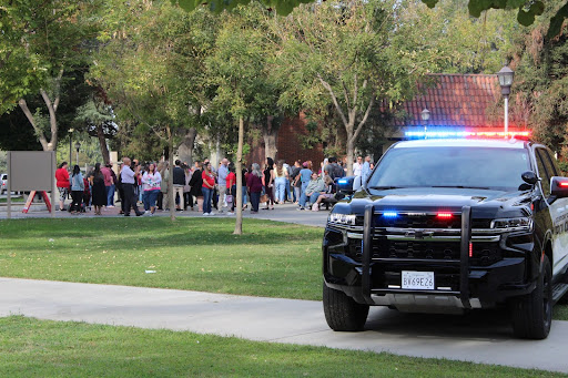 Students, staff, and faculty gather by the small fountain in front of the Old Administration Building with campus police on standby during the evacuation part of the earthquake drill at Fresno City College, Oct. 20, 2022.