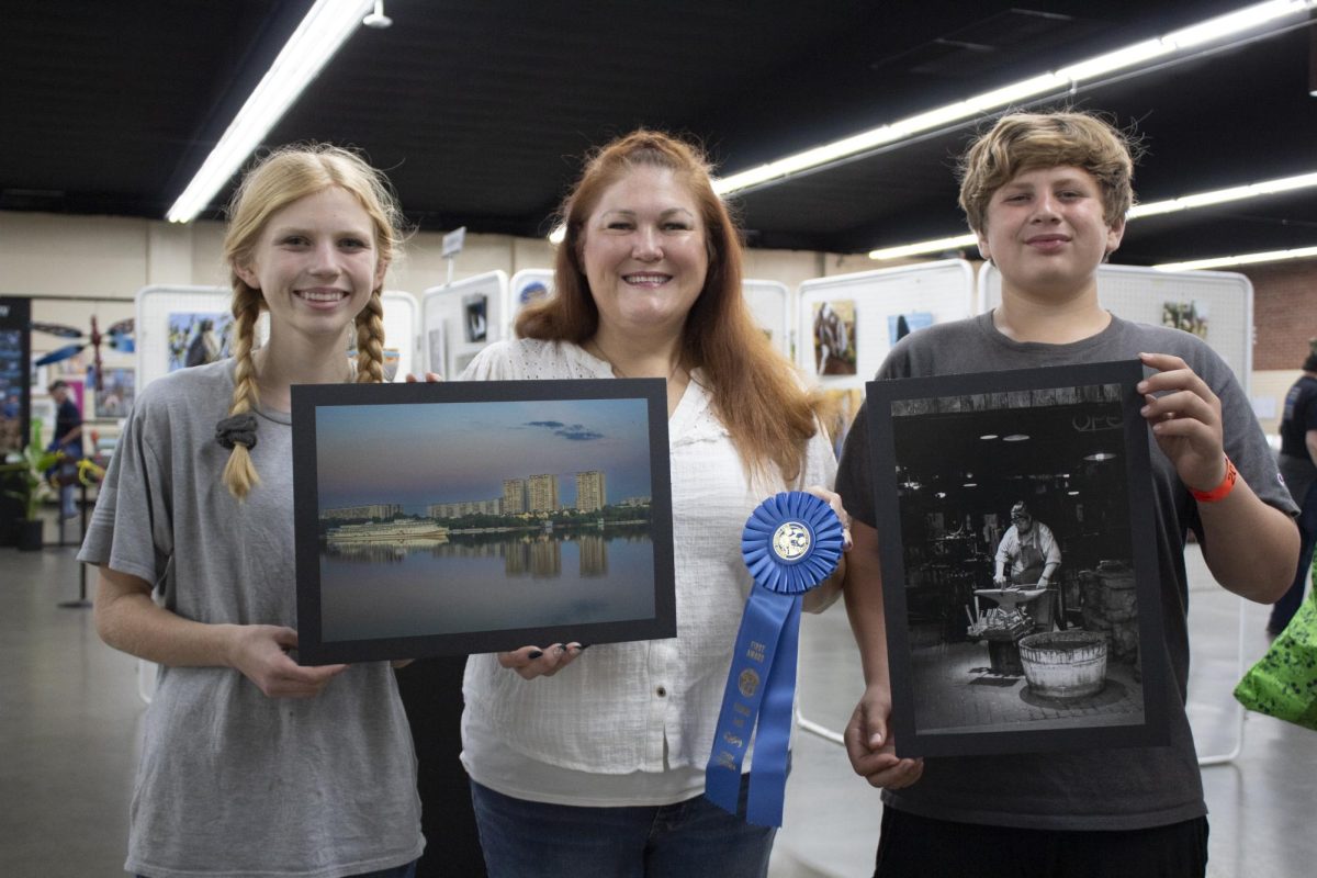 Jannet Moore (center) posing with two members of her 4-H youth group {left and right} holding two of her three award winning photo submissions 