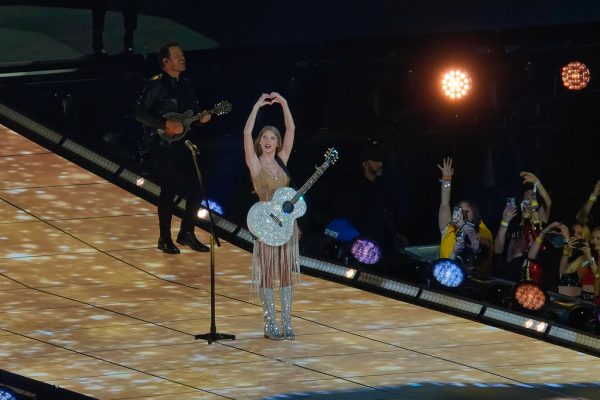 Taylor Swift doing her iconic “Fearless” heart hands on stage for The Eras Tour in Arlington, Texas. 