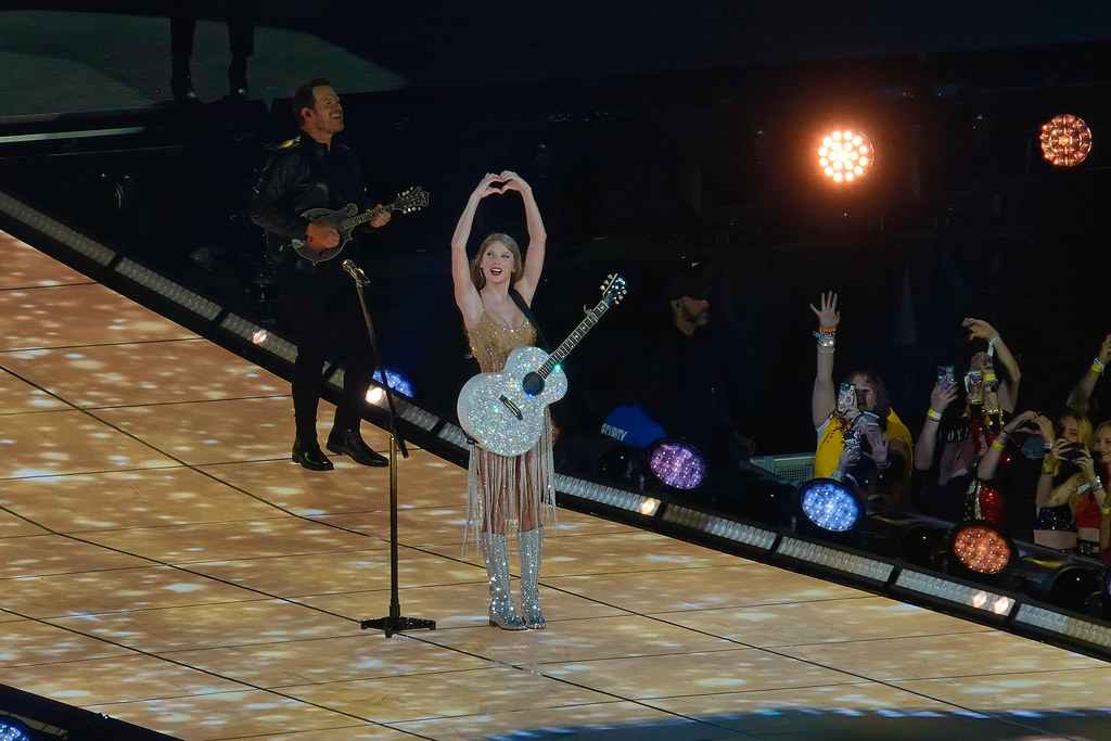 Taylor Swift doing her iconic “Fearless” heart hands on stage for The Eras Tour in Arlington, Texas. 