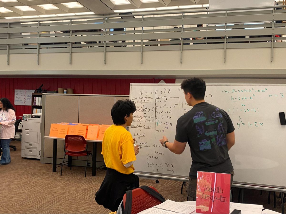 Kyle Wong teaches drop-in math tutoring in the busy tutorial center as embedded tutoring lessons function above on Feb. 21, 2024.