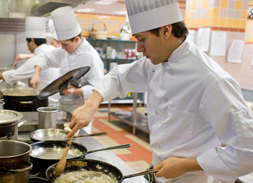 A group of students that are learning how to cook in the kitchen in 2009.