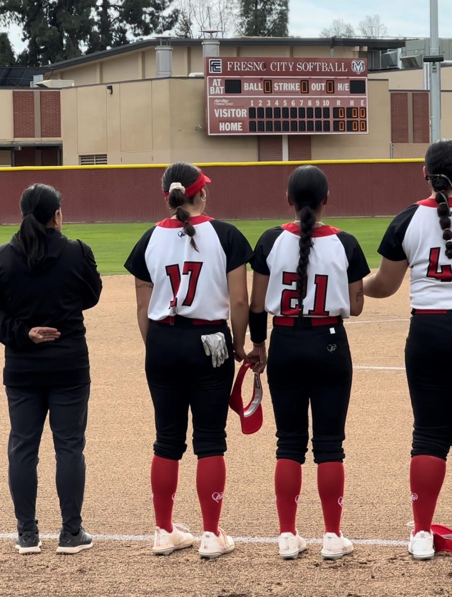 Fresno City College women’s softball head coach, Linda Garzaand her players sitting for the national anthem at their game on March 5. 
