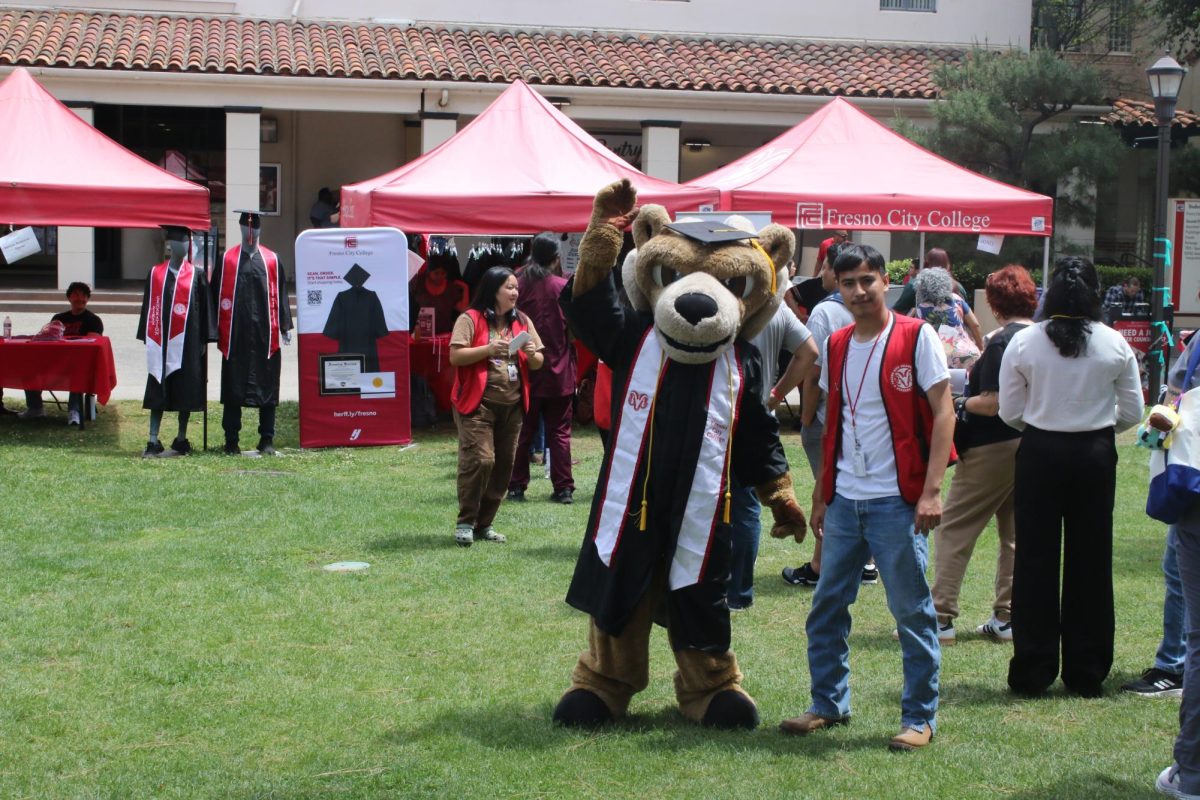 Sam the Ram, Fresno City College's mascot, poses in the middle of the graduation fair on April 30 next to Miguel Barrita, a FCC student majoring in anthropology. Students who attended this event were able to purchase cap and gowns and pick up cords for the different programs.