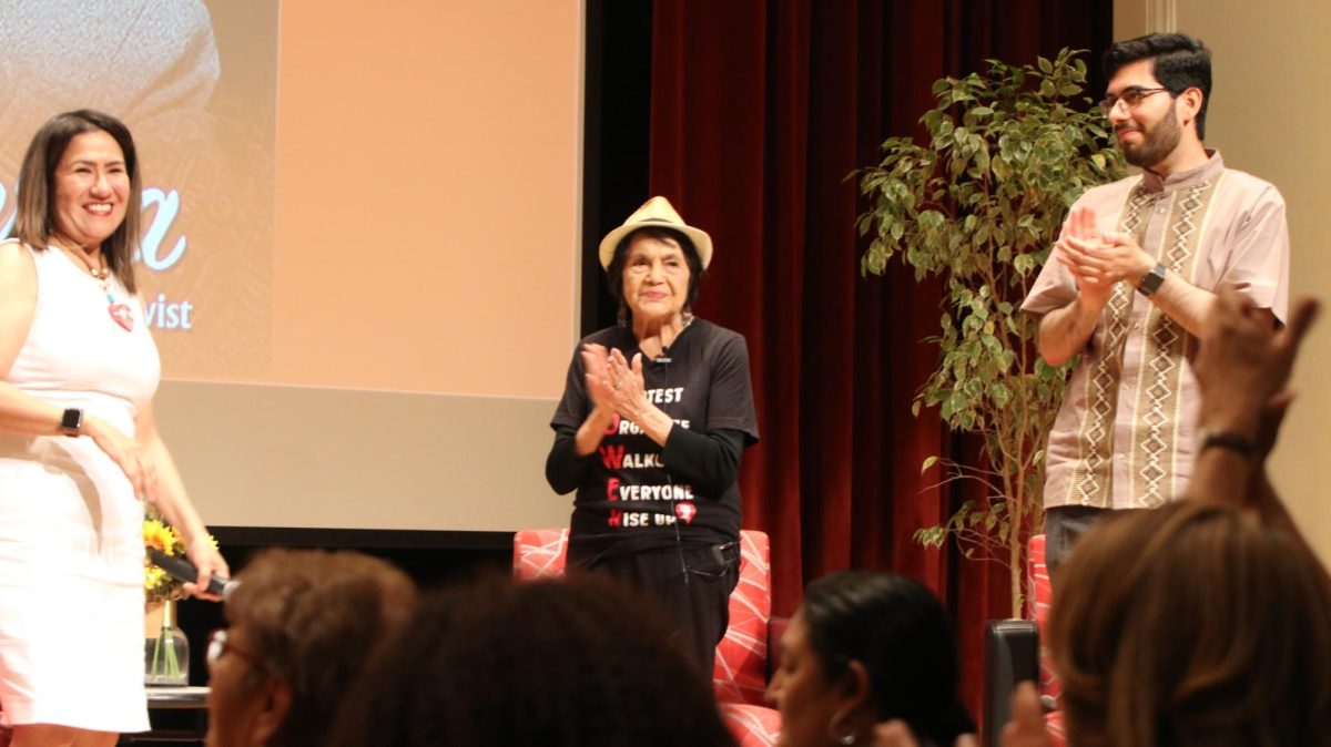 Lori Natal (left), Dolores Huerta (middle), and Francisco Bucio (right) clapped after the crowd completed a small exercise Huerta made to help unify the Latino community.  