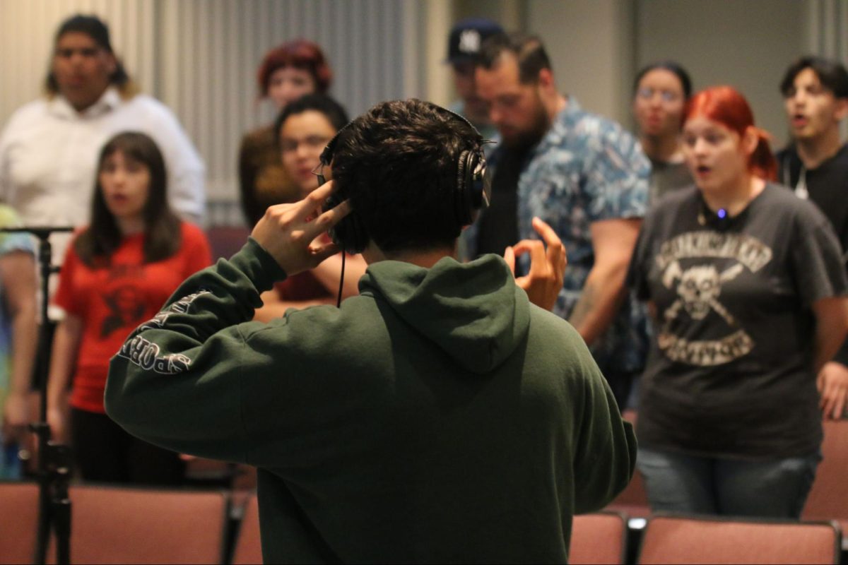 Julian Michael Mendoza conducts and records a group of 14 Fresno City College choir singers as they sing vocals for the intro track of his upcoming EP in the recital hall on May 8, 2025.