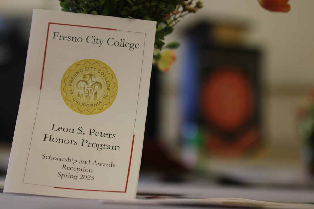 The program for the Leon S. Peters Honors Scholarship and Awards Reception rests upon a vase of flowers on one of the many tables facing the podium in OAB-114 on May 7, 2025.