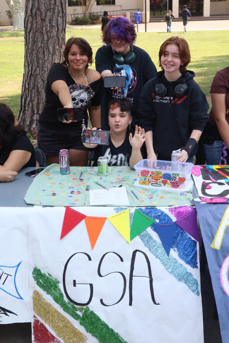 (left to right) Zoey Aragon, Beetle Witt, Sunny Genini and Apollo Juarez (sitting) hold their phones to reveal footage of "Subway Surfers" and "Minecraft" gameplay videos, along with a Markiplier Youtube video in an effort to grab students' attention and promote the Gender and Sexuality Association at Fresno City College during club rush on Aug. 29, 2025.
