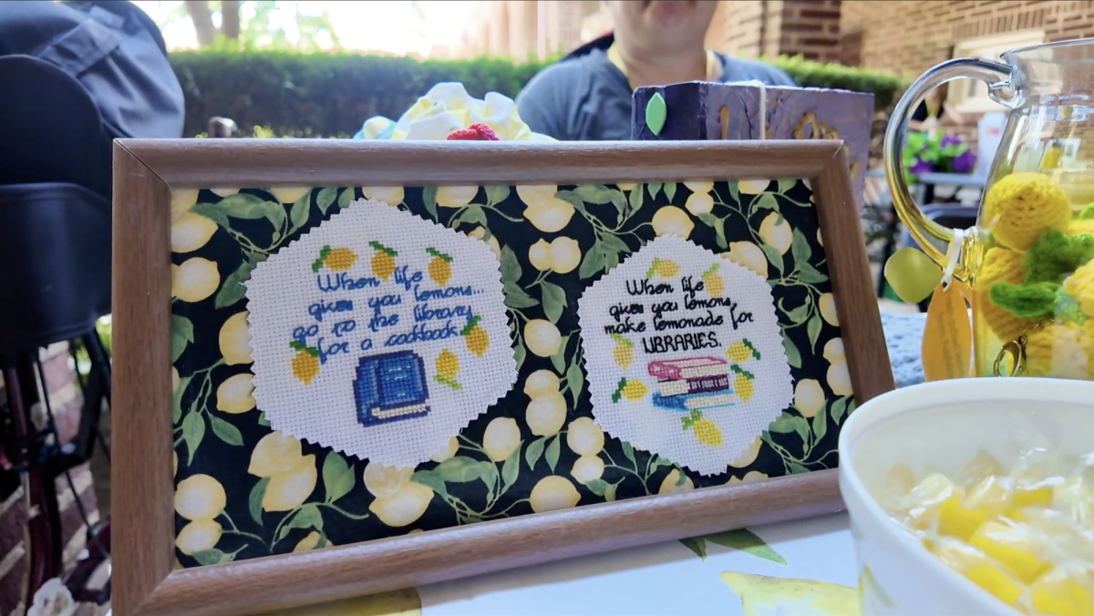 Brooke Payton sits at a booth promoting the Tower District Library Project during the Queer Housing Summit on Aug. 23 at Fresno City College, complete with hand-crafted crochet lemons and signs which read "When life gives you lemons, go to the library for a cookbook" and "When life gives you lemons, make lemonade for libraries." 