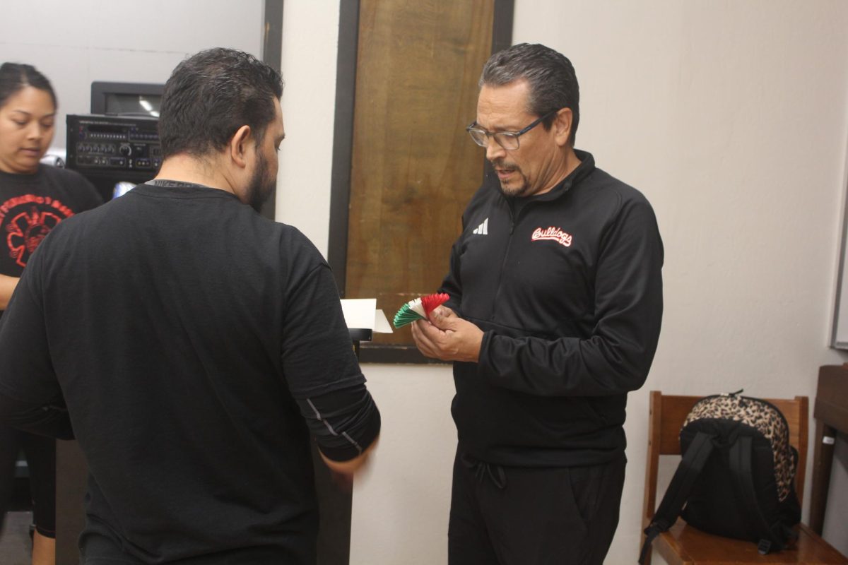 Victor Torres shows Artemio Quintana how to create a prop for one of their dances during their class on Oct. 13.