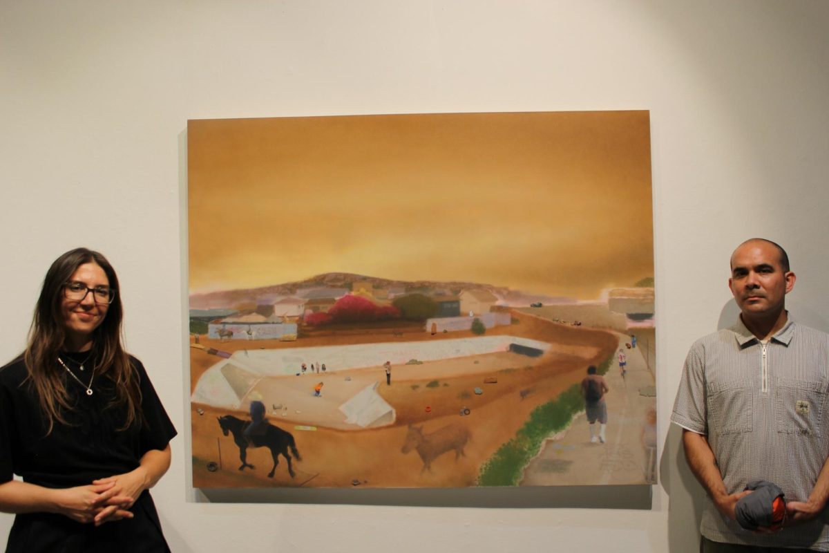 Art Department instructor Elena Harvey Collins (left) and Artist Micahel Alvarez, stand between Alvarez’s painting titled “The Wedge” on Oct. 2, 2025.
