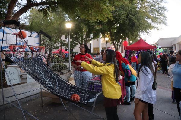 Carnival-goers shoot a basketball at carnival game near a club's booth, Oct. 24.