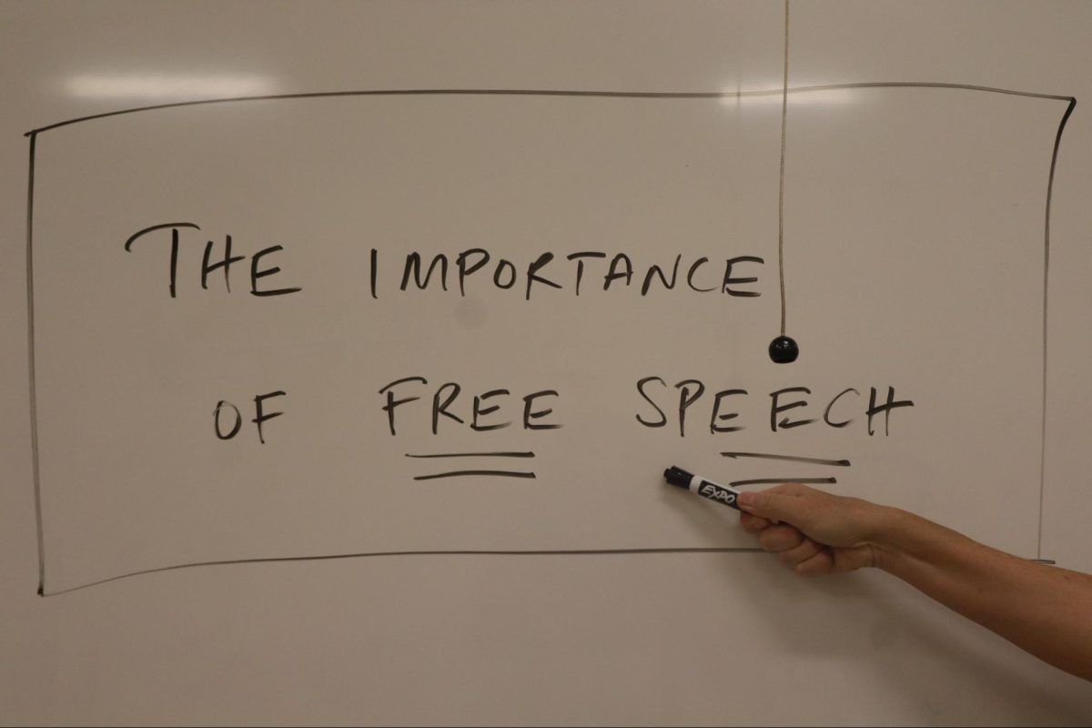 Professor Barri Brennan poses and gestures to a whiteboard with the phrase "the importance of free speech" in one of her Fresno City College classes. This is a staged photo and not a part of Brennan's lecture.