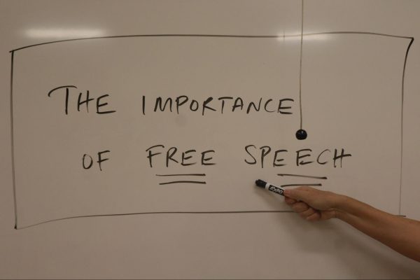 Professor Barri Brennan poses and gestures to a whiteboard with the phrase "the importance of free speech" in one of her Fresno City College classes. This is a staged photo and not a part of Brennan's lecture.
