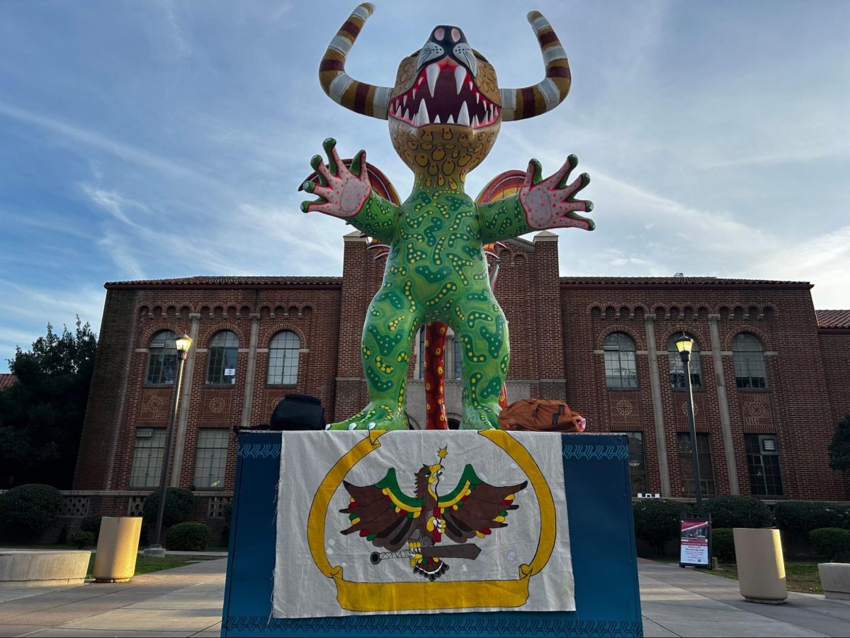 An artistic Mexican animal sculpture, part of Arte Américas “Fantastic Animals From Mexico” exhibit, stands in front of the Fresno City College library with MEChA’s flag underneath on Feb. 26.
